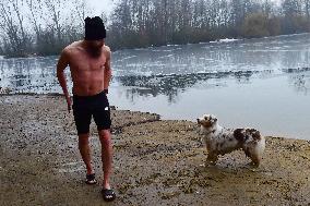 young man bathes in ice water in the natural swimming pool, dog