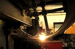 A worker processes pressure vessel equipment at a workshop of La