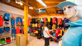 Shop Hudysport with outdoor and sports equipment, sales assistant, customer, face mask