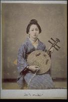 A woman playing the gekkin (a stringed instrament of Chinese origin)