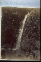 Children bathing in the basin of a waterfall and onlookers