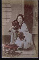 A geiko playing the tsuzumi (a traditional drum)