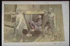 A woman in a basket palanquin