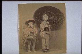 A girl holding an umbrella and her attendant wearing a straw raincoat
