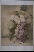 A man and a woman covering their heads under the same unbrella