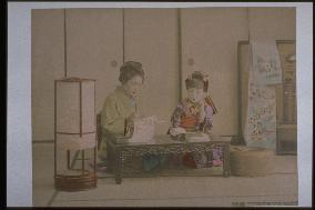 A mother reading a book and writing a letter