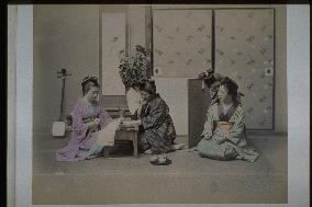A woman writing a letter,and whispering girls
