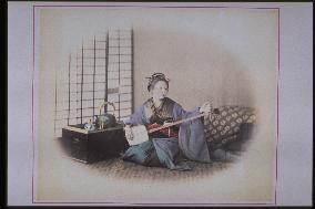 A woman playing the shamisen,and a box brazier