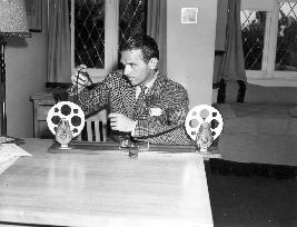 Film actor, DOUGLAS FAIRBANKS JR, at home looking at some 16