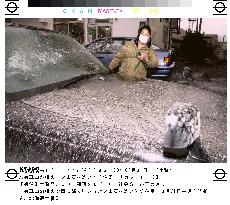 Resident washes car covered with ash from volcano