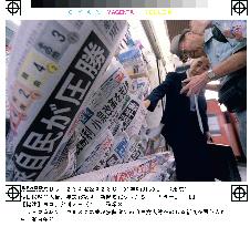 People buy papers reporting LDP's election victory