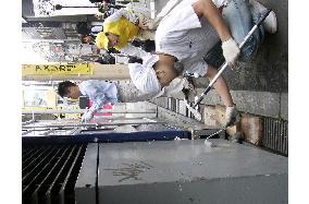Volunteers scrub off graffiti at America Mura in Osaka