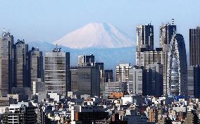Snow-covered Mt. Fuji seen far behind Tokyo buildings