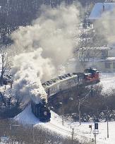 Old steam locomotive chugs through snowy Hokkaido