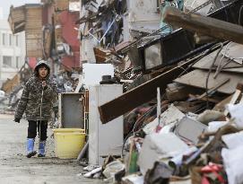 Boy walks beside rubble