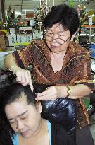 Thai woman makes good living by plucking gray hairs