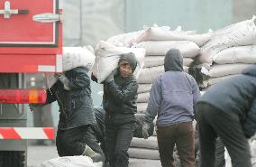 North Korean workers carry bags from truck