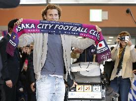 Uruguay striker Forlan holds up scarf upon arrival in Japan