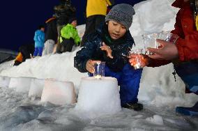 Child sets up candle on quake anniversary in Nagano village