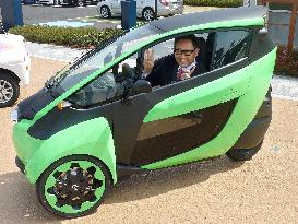 Toyota Motor chief gives victory sign in small electric vehicle