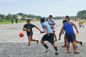 Young men play football on airport runway in Tuvalu