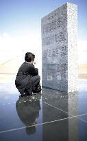 Woman weeps before monument for March 2011 victims