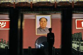 Armed policeman keeps guard before Mao's portrait