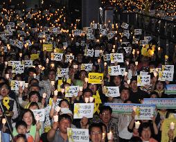 Mourners hold candles at ferry disaster memorial event