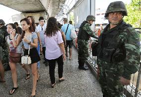 Citizens walk past solders standing guard in Bangkok