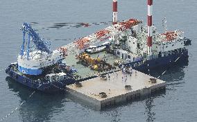 Close scrutiny of overturned pier off Kagoshima City