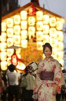 Woman in 'yukata' walks before float at Kyoto festival