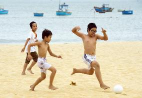 Vietnamese children play soccer on beach