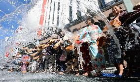 People splash water on car-free street in Tokyo's Ginza