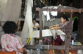 Thai Women weave silken fabrics using loom
