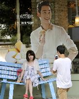 Chinese woman poses in front of S. Korean actor's poster