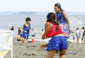 Young people enjoy water balloon fight on Japan beach