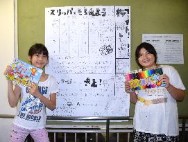 Handwritten newspaper for mudslide evacuees by student pair