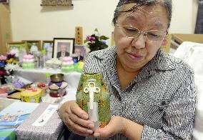 Woman holds urn with soil from home in memory of husband
