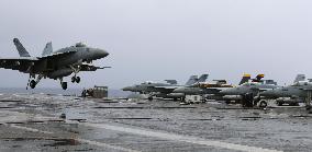 F/A-18 jet touching down on aircraft carrier in drill