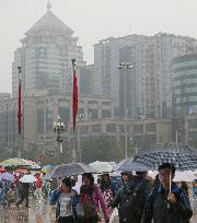 People walk on smoggy, rainy National Day in Beijing