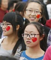 Women with China's flag seals watch Nat'l Day ceremony