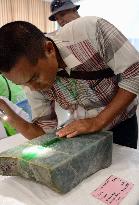Buyer examines gemstone at Myanmar's gem emporium
