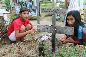 Filipino girl offers flowers to brother's grave