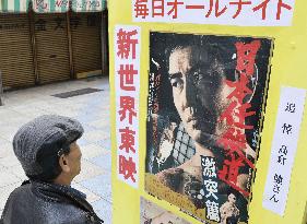 Man looks at movie poster featuring actor Takakura
