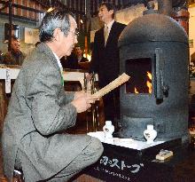 Feed wood in replica of Japan's 1st stove in Hokkaido