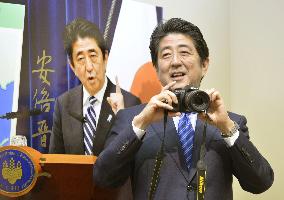 PM Abe holds camera at press photo exhibit