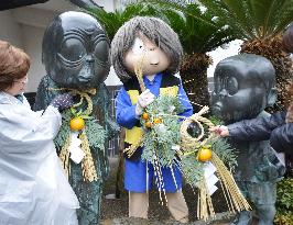 Kitaro hangs New Year decoration on bronze statue