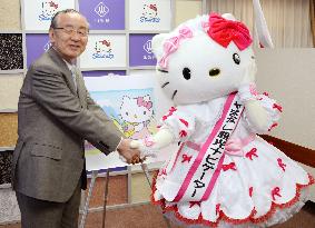 Yamanashi Gov. Yokouchi shakes hands with Hello Kitty