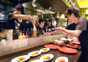 Employees prepare hot dogs in Nipponham travel cafe in Osaka