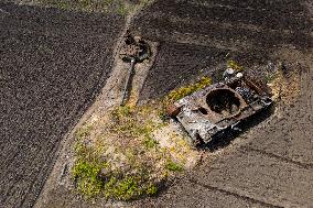 A Local Resident Plants Plants Next To A Destroyed Russian Tank, The Remains Of Which Lie In His Garden